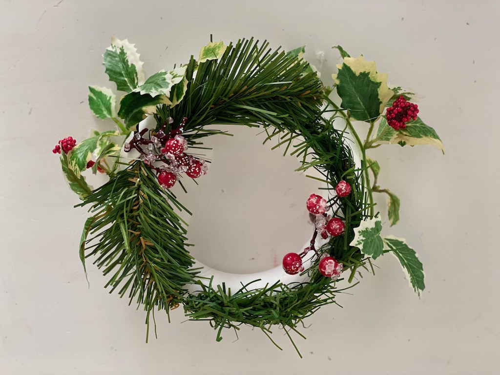 This DIY Christmas wreath is made easily by a child with artificial greenery and a foam ring.