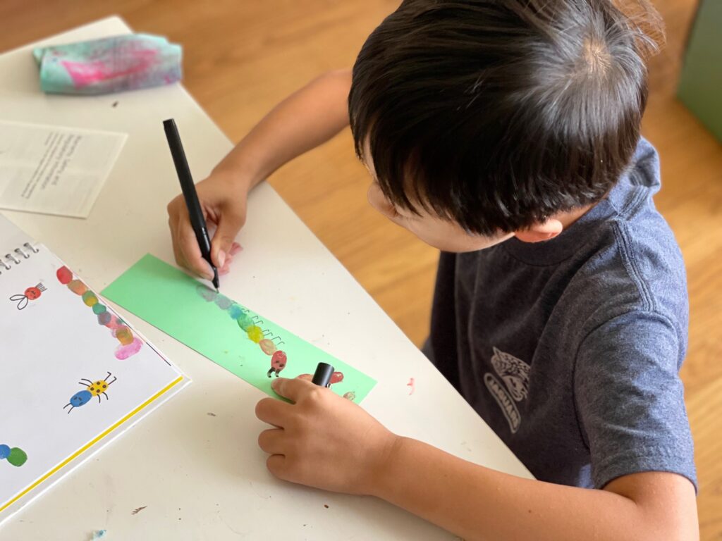 Child makes a caterpillar using his fingerprints to make a bookmark for his dad.