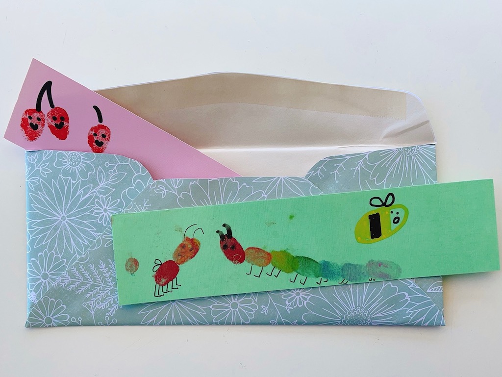 Two fingerprint art bookmarks: One shows a caterpillar and ant made with fingerprints; the second, smiling cherries.