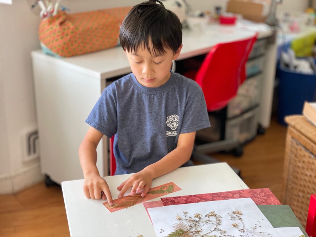 Child makes pressed flower bookmarks for his Father's Day gift.