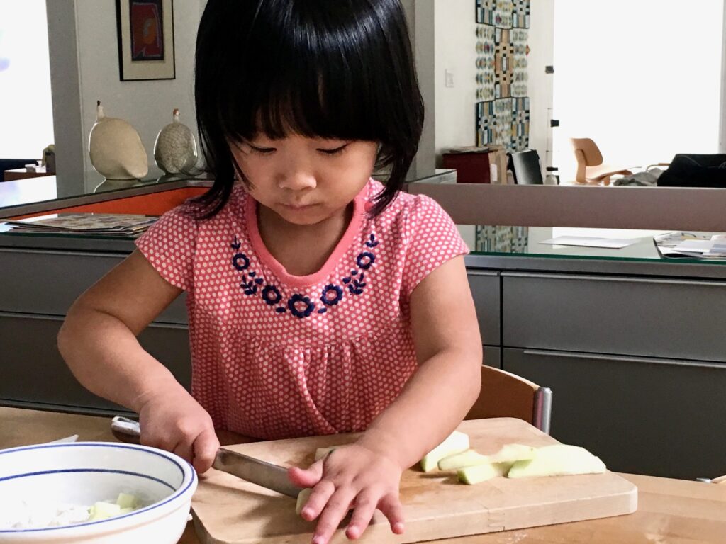 Child cuts apples with a table knife to make an easy snack.