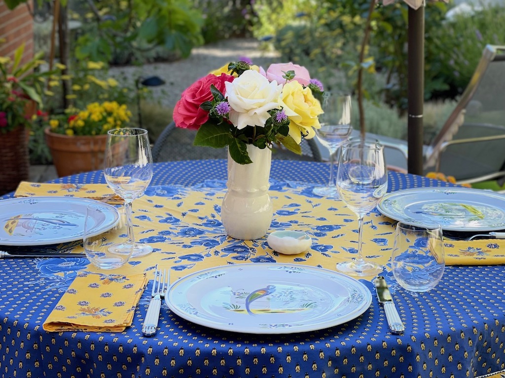 Table setting in a garden with roses and French tableware.