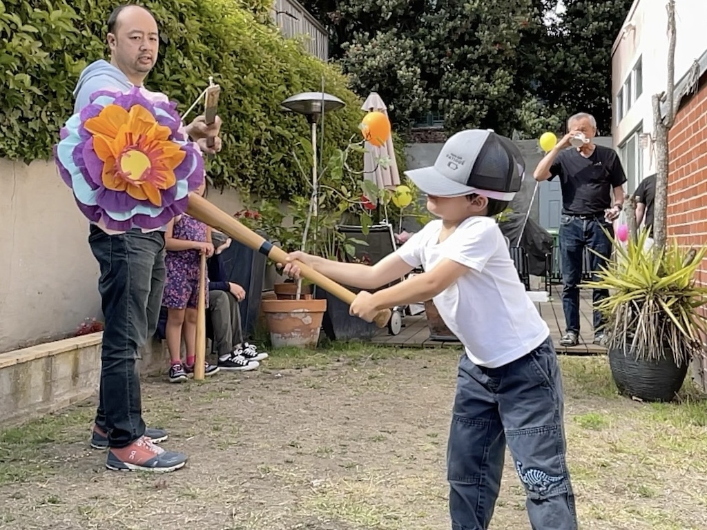 Child hittin the piñata with a baseball bat.