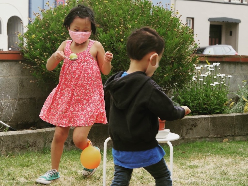 Grandkids do a spoon relay race, masked during the 2020 pandemic.