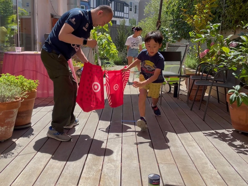 Child runs with a shopping bag to pick up a grocer item in this "Bring Home the Bacon" relay race.