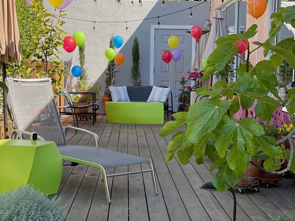 Deck is decorated for a summer kids' party with colorful balloons. All the deck furniture is moved to the side to make way for games.