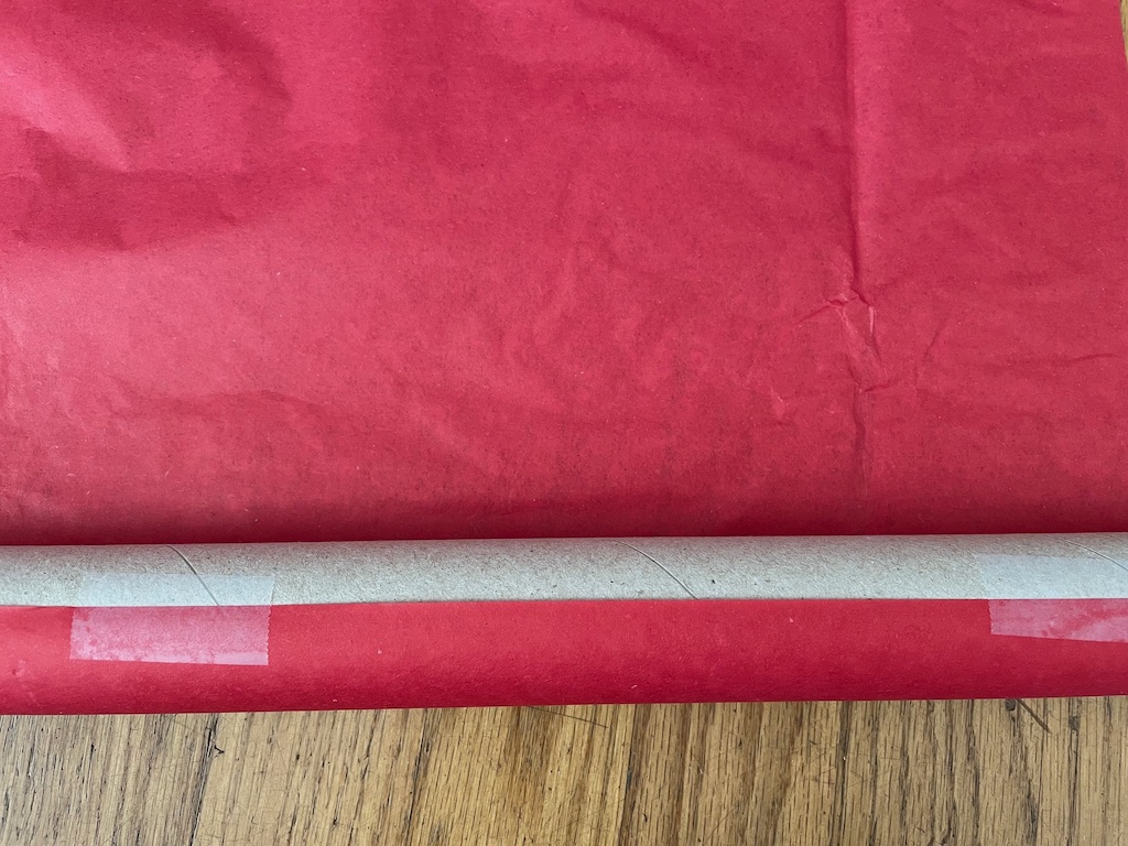 The first step to make a lightsaber: start wrapping tissue paper by first taping it to the cardboard tube.