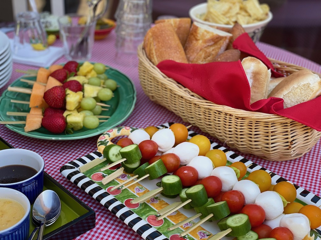 Food for a summer kids' party: fruit and vegetable skewers and hot dogs.