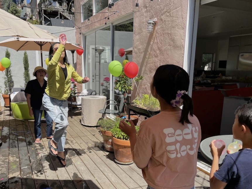 A member of one team tossed a water balloon through a hoop made from a wire hanger. The opposite team tries to catch it.