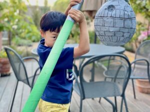 Child tries out DIY lightsaber for a Death Star piñata.