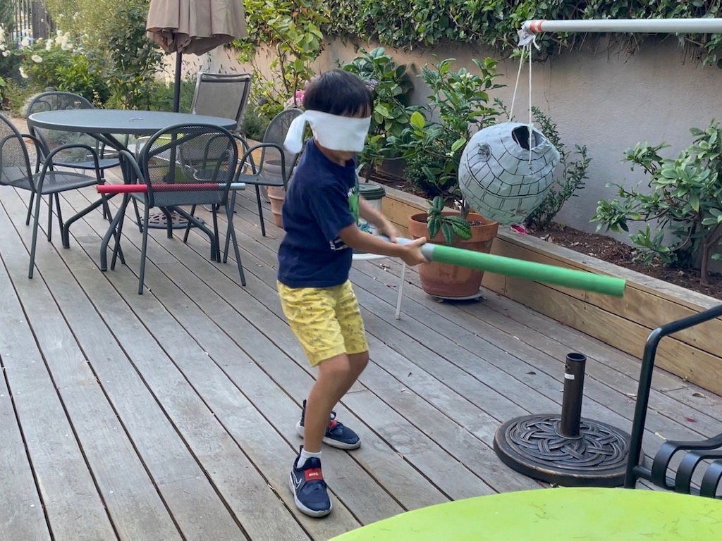 Blindfolded child swings at the Star Wars Death Star piñata.