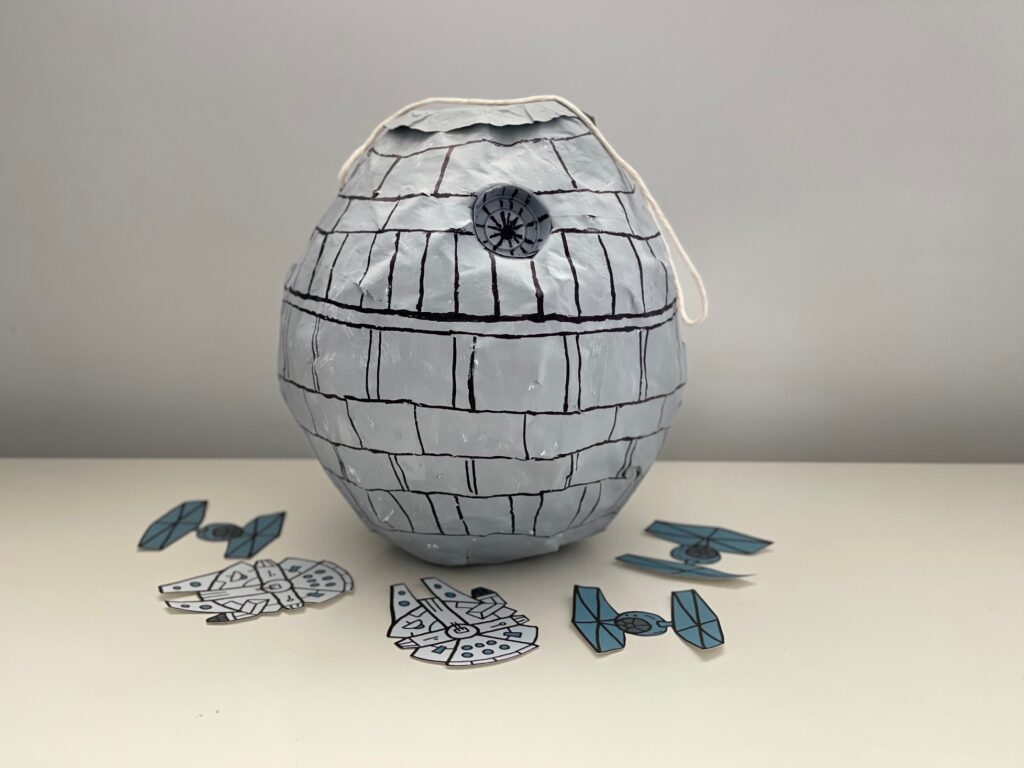 This Star Wars Death Star piñata is made with old newspapers, a plastic sauce cup, a balloon, and some paint.