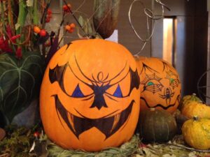 Pumpkins are turned into jack-o-lanterns by drawing faces with markers.