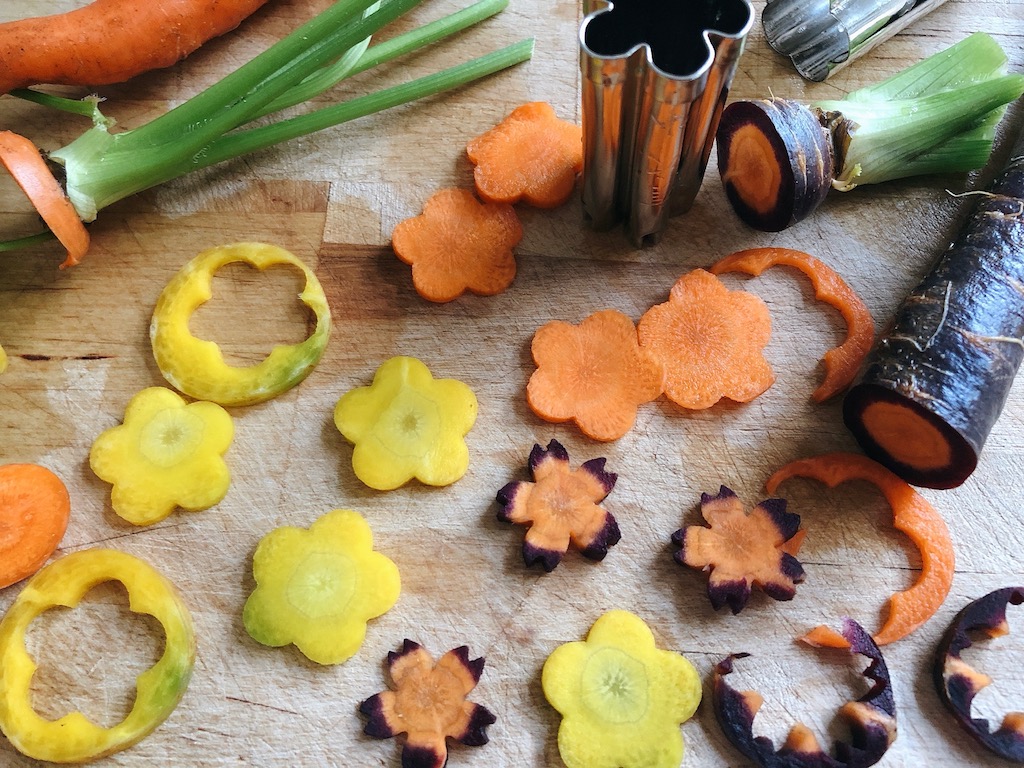 Carrot slices are cut into flower shapes with a vegetable cutter.