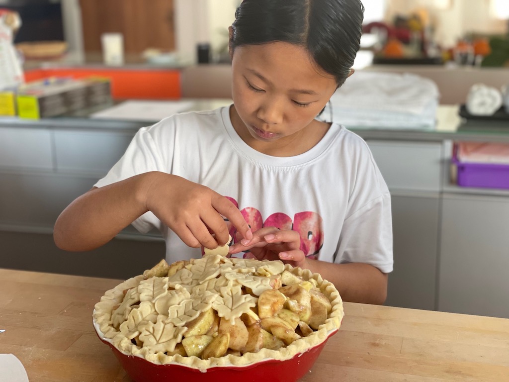 Miss T adds pastry leaves to the Thanksgiving apple pie.