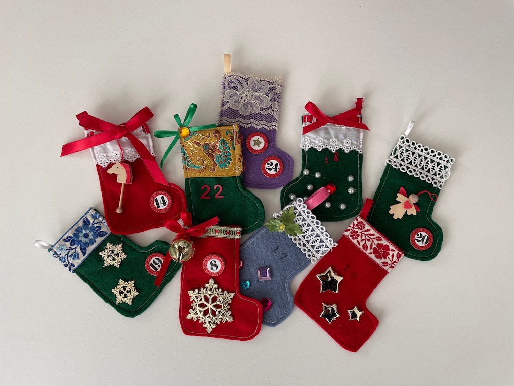 A variety. of tiny stockings are decorated and numbered for an Advent calendar.