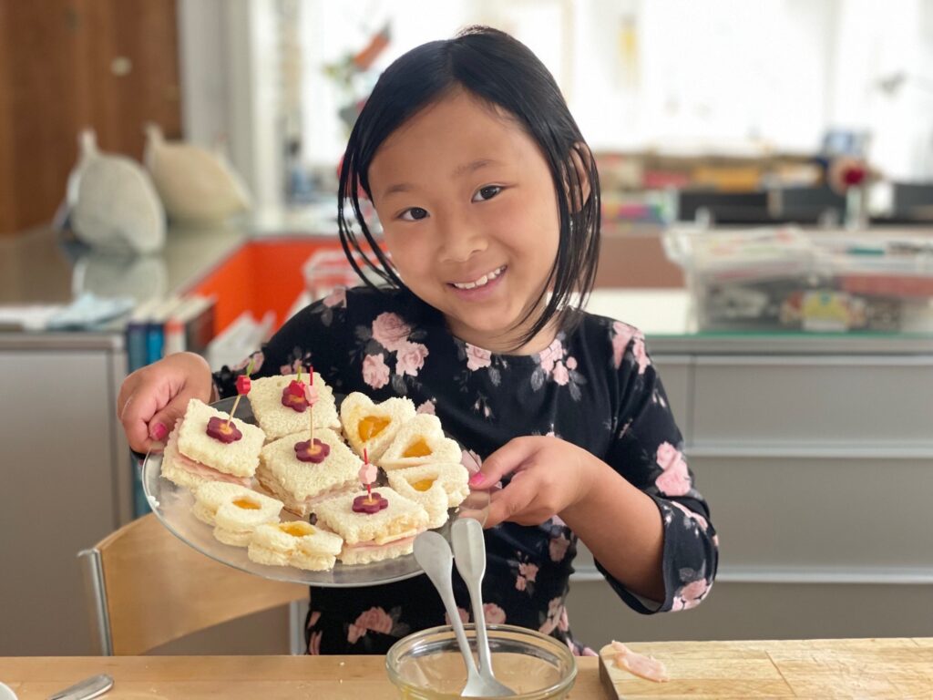 Child shows off tea sandwiches she made.