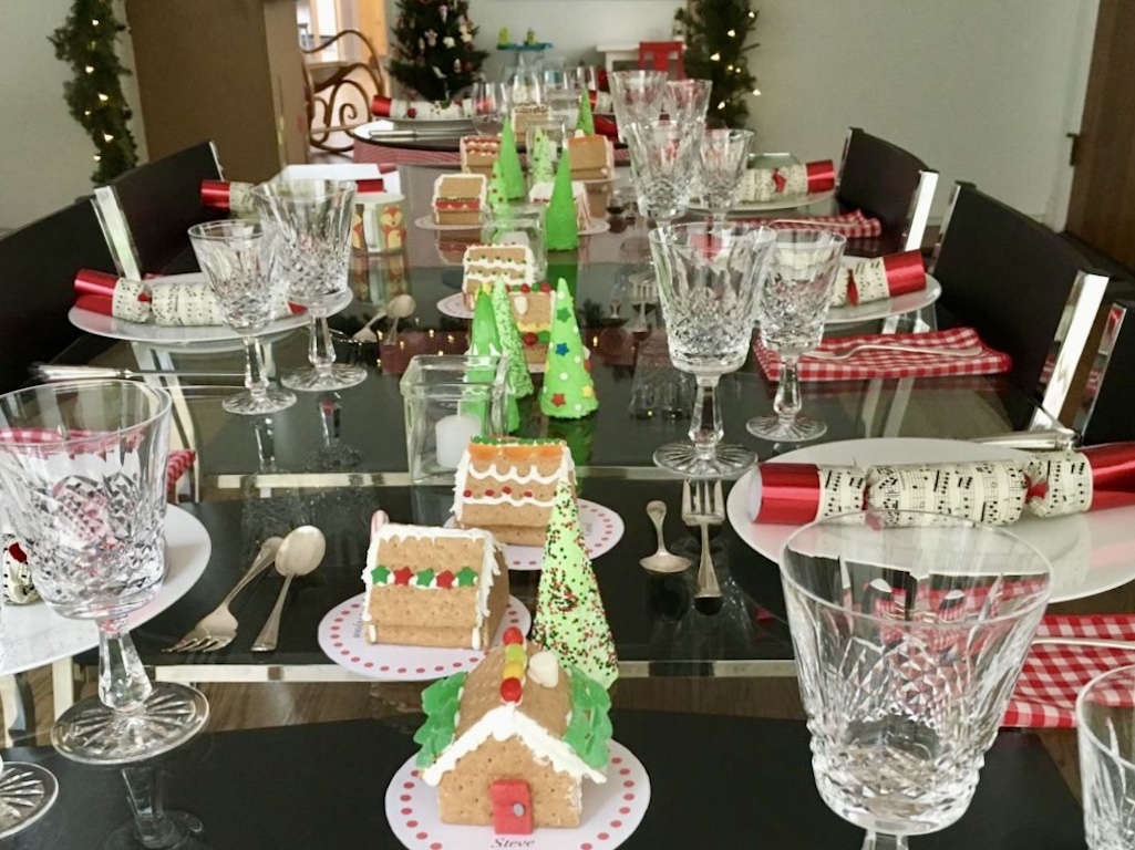 Gingerbread houses are made from graham crackers. Ice cream cones are frosted to become Christmas trees in this charming table setting.