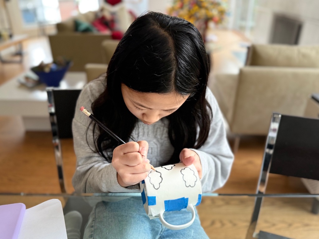 Child retraces her design on the mug to transfer the design.