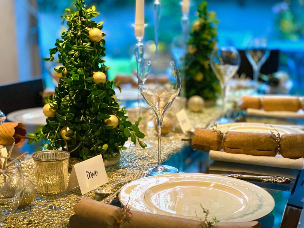 Christmas trees are made out of boxwood sprigs in wet foam cones. They are the centerpiece for a fresh greens and gold Christmas table setting.