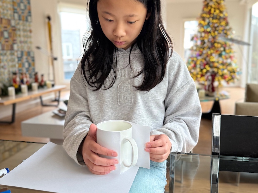 Cut a strip of paper to the height and width of the mug. Draw your design on the paper first.