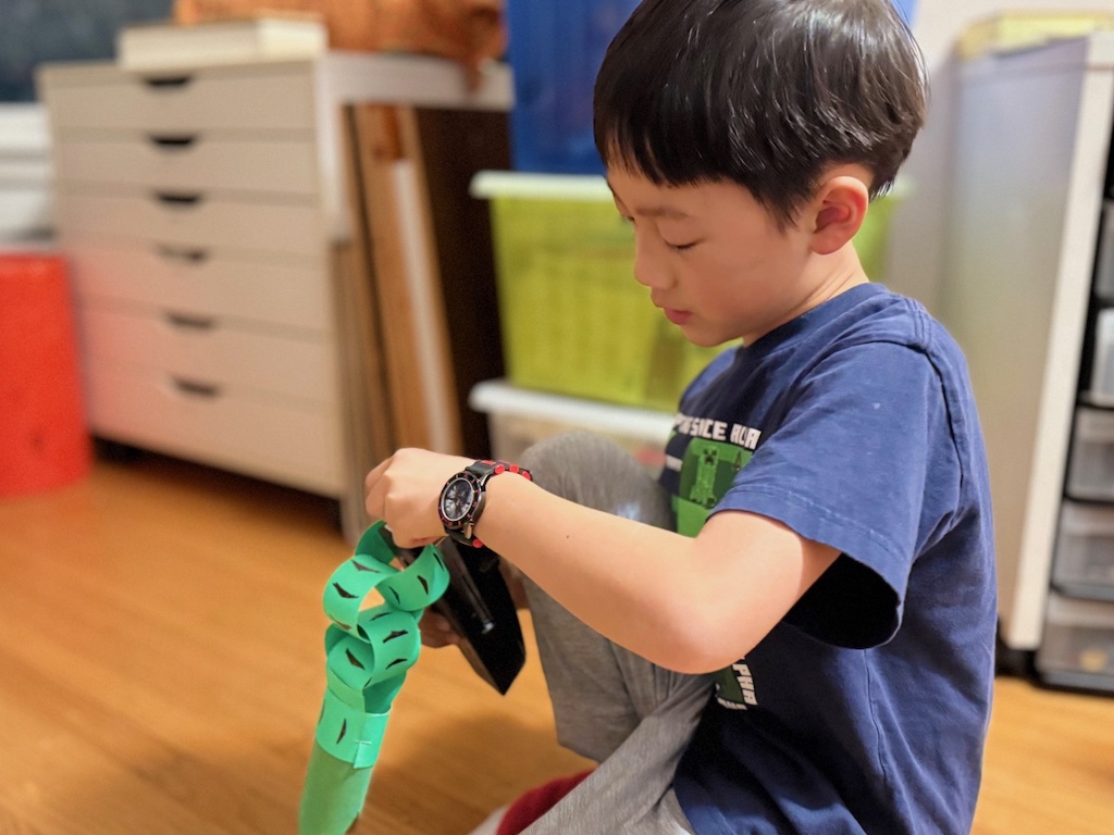 Child staples cardstock to make paper chains as an alternative to gluing.