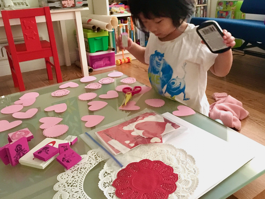 A child of three makes Valentine's Day cards.