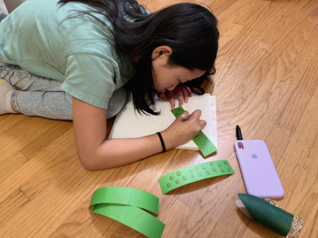 Child draws snakeskin pattern on cardstock strips to make her DIY Chinese New Year dragon.