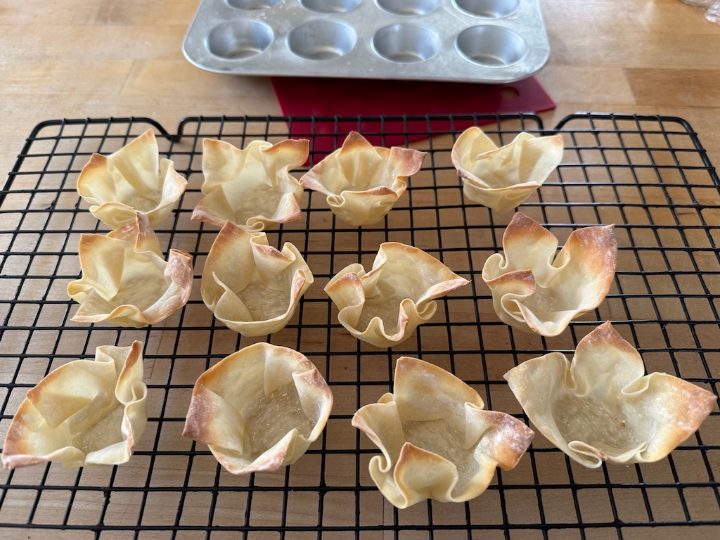 Baked wonton cups cool on a rack.