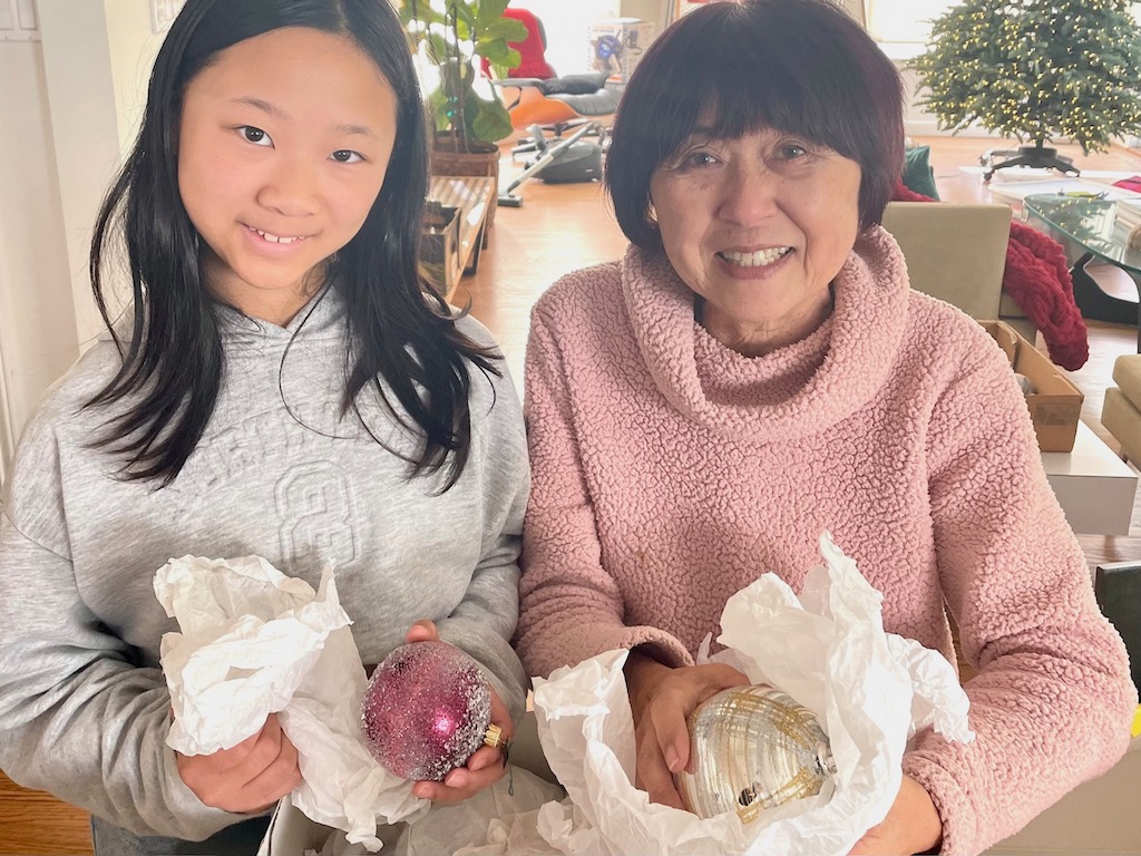 Grandma and granddaughter unwrap ornaments for the Christmas tree.