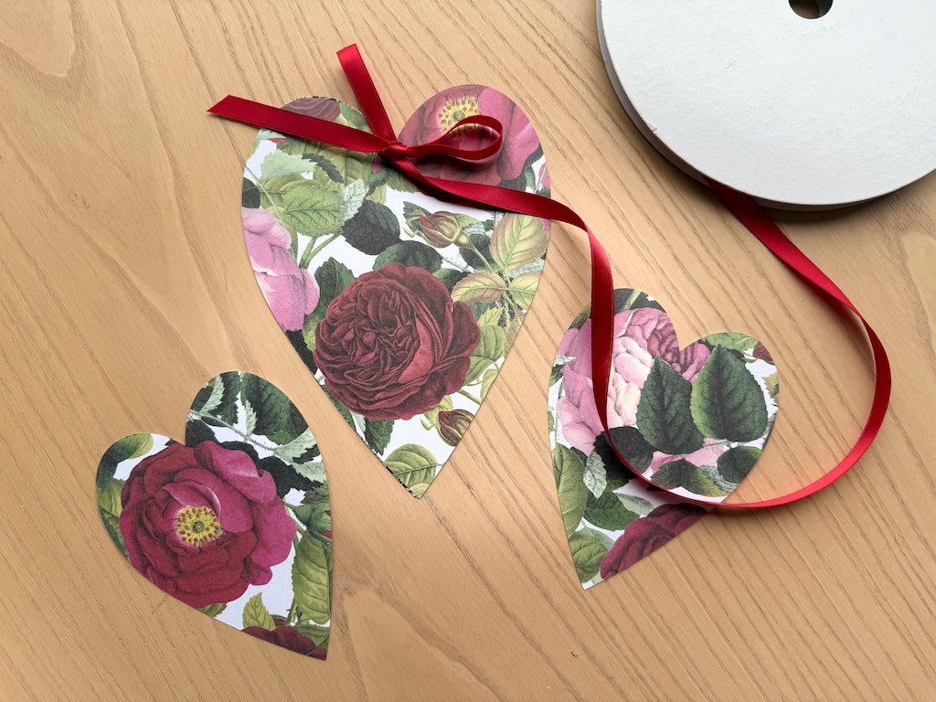 Cardstock hearts in floral patterns are ready to be tied with  ribbons to decorate the table.