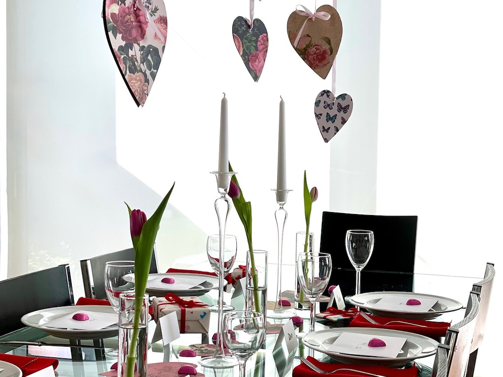 For a family Valentine's party, decorate the table with cardstock hearts, a few flowers in bud vases, and red napkins. Use everyday plates and stemware that go into the dishwasher.