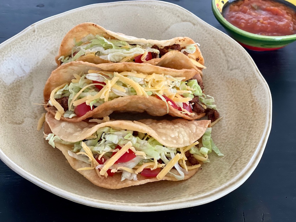 Easy-to-make taco filling is nested. into crisp taco shells with lettuce and tomato.