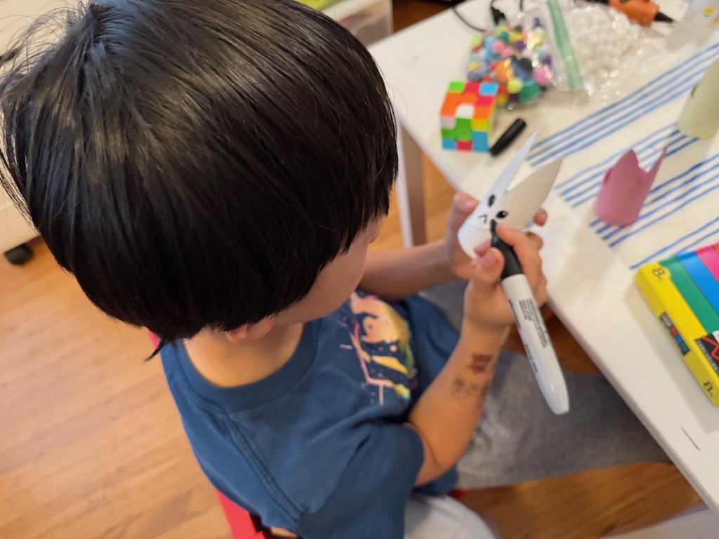 Child draws a face on a toilet roll Easter bunny.