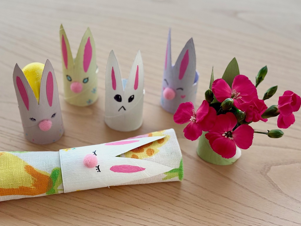 Some toilet roll Easter bunnies demonstrating their uses: Napkin ring, Easter egg carrier, and flower vase.