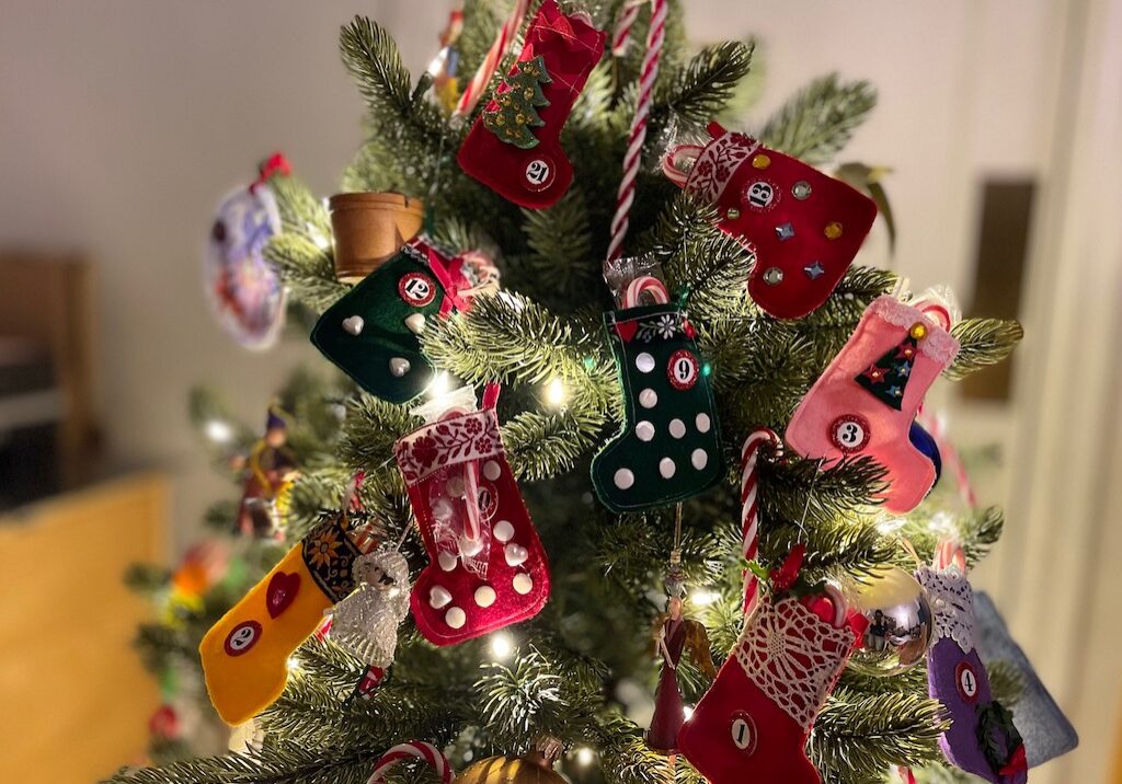 Tiny Christmas stockings sit on a small Christmas tree for a novel Advent calendar.