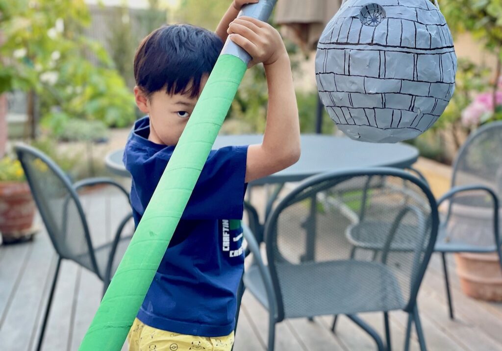 Child tries out DIY lightsaber for a Death Star piñata.