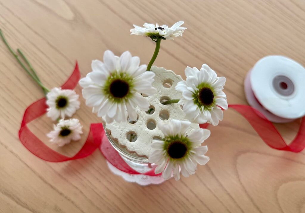 Flower frog made from air-dry clay, sits on a glass jar vase. Arrange flowers in the holes.