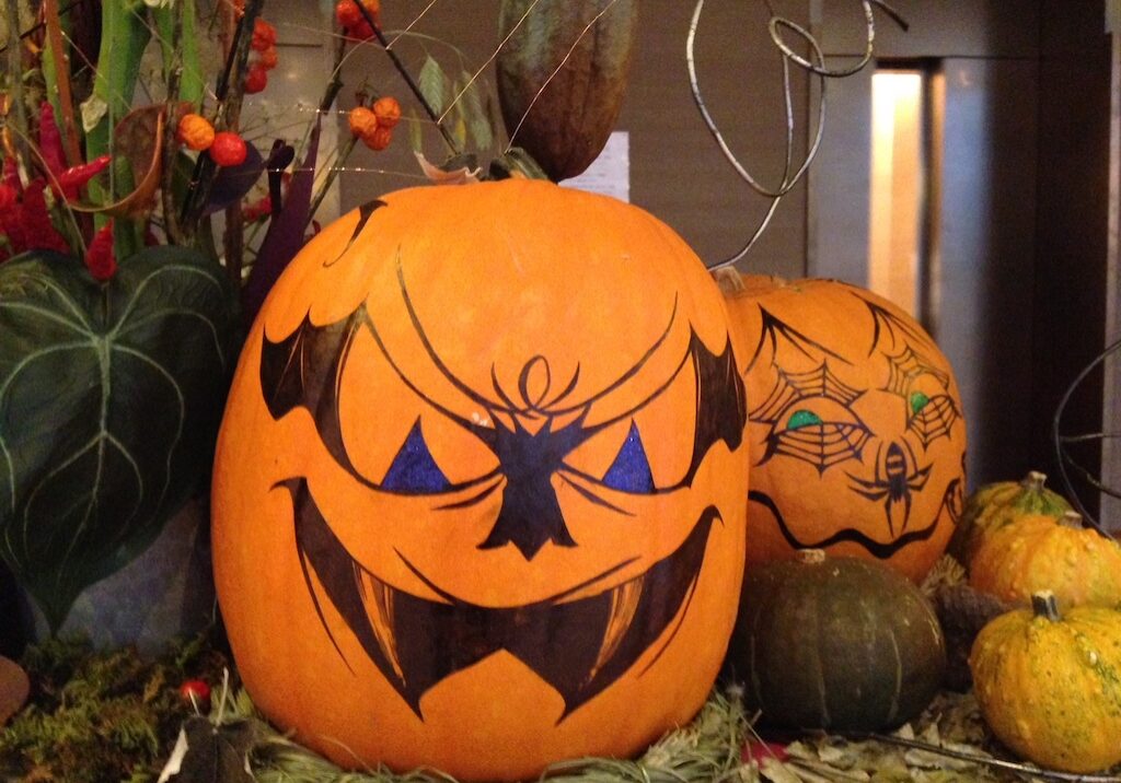 Pumpkins are turned into jack-o-lanterns by drawing faces with markers.